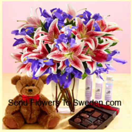 الزنابق الوردية والزهور البنفسجية المتنوعة مرتبة بشكل جميل في وعاء زجاجي، دمية دب بني طوله 12 بوصة وصندوق مستورد من الشوكولاتة