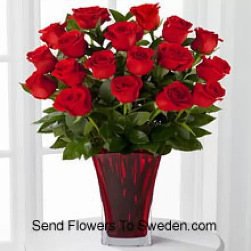 19 roses rouges avec des remplissages saisonniers dans un vase en verre décoré d'un nœud rose